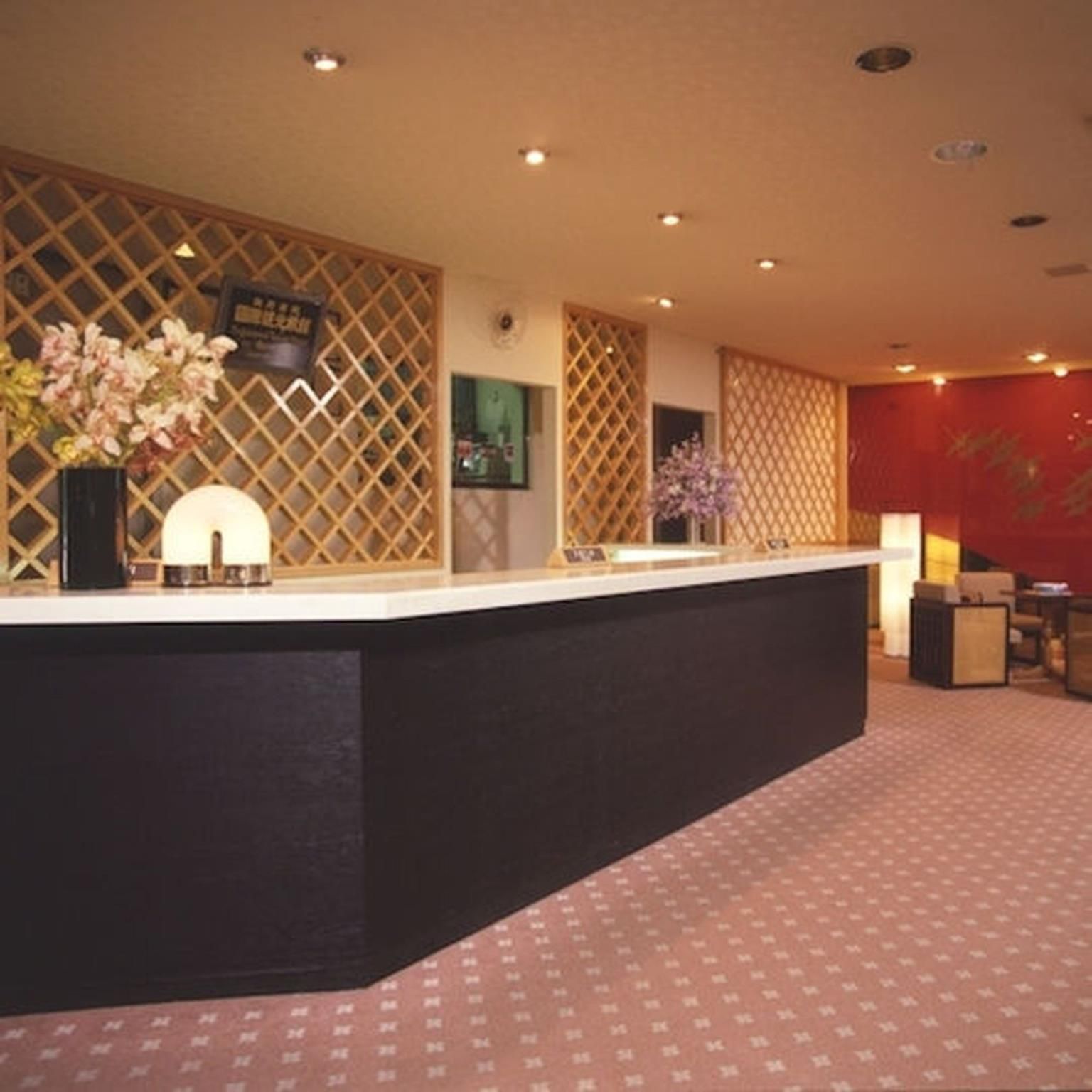 A reception desk with a patterned carpet, a decorative wall with lattice panels, and a red accent wall.