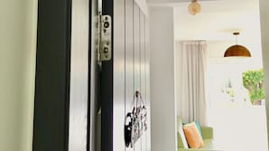 Una habitación con una puerta de madera, una bombilla colgante y un sofá verde al fondo.