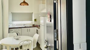 Una cocina moderna con armarios blancos, un refrigerador de acero inoxidable y una lámpara colgante.