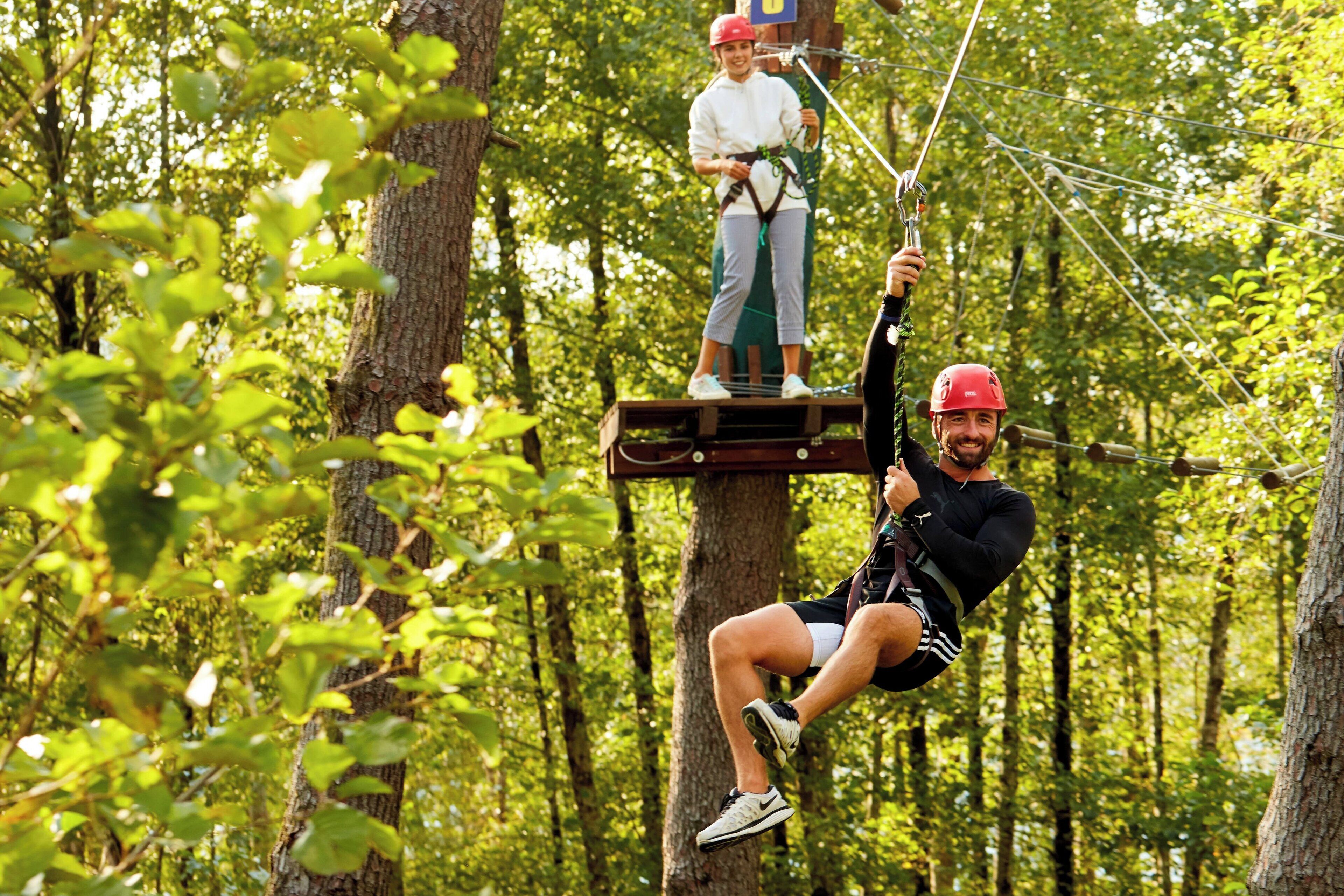 A person zip-lining through a forest.