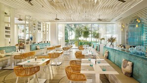 A modern restaurant with white furniture, a patterned ceiling, and large windows offering a view of greenery. - Autograph Collection Paragraph Resort & Spa Shekvetili (Shekhvetili)