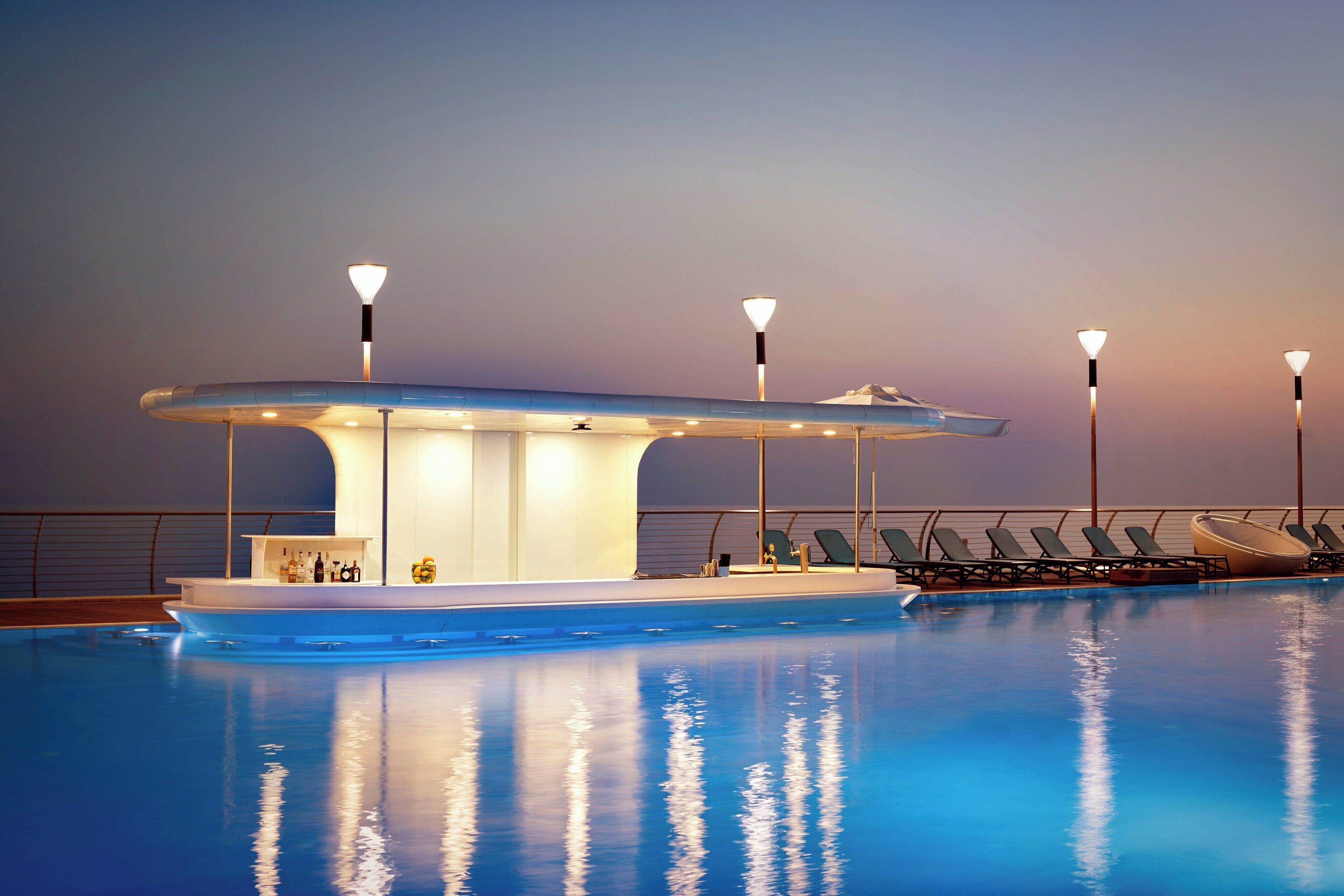 A pool area with a bar and lounge chairs.