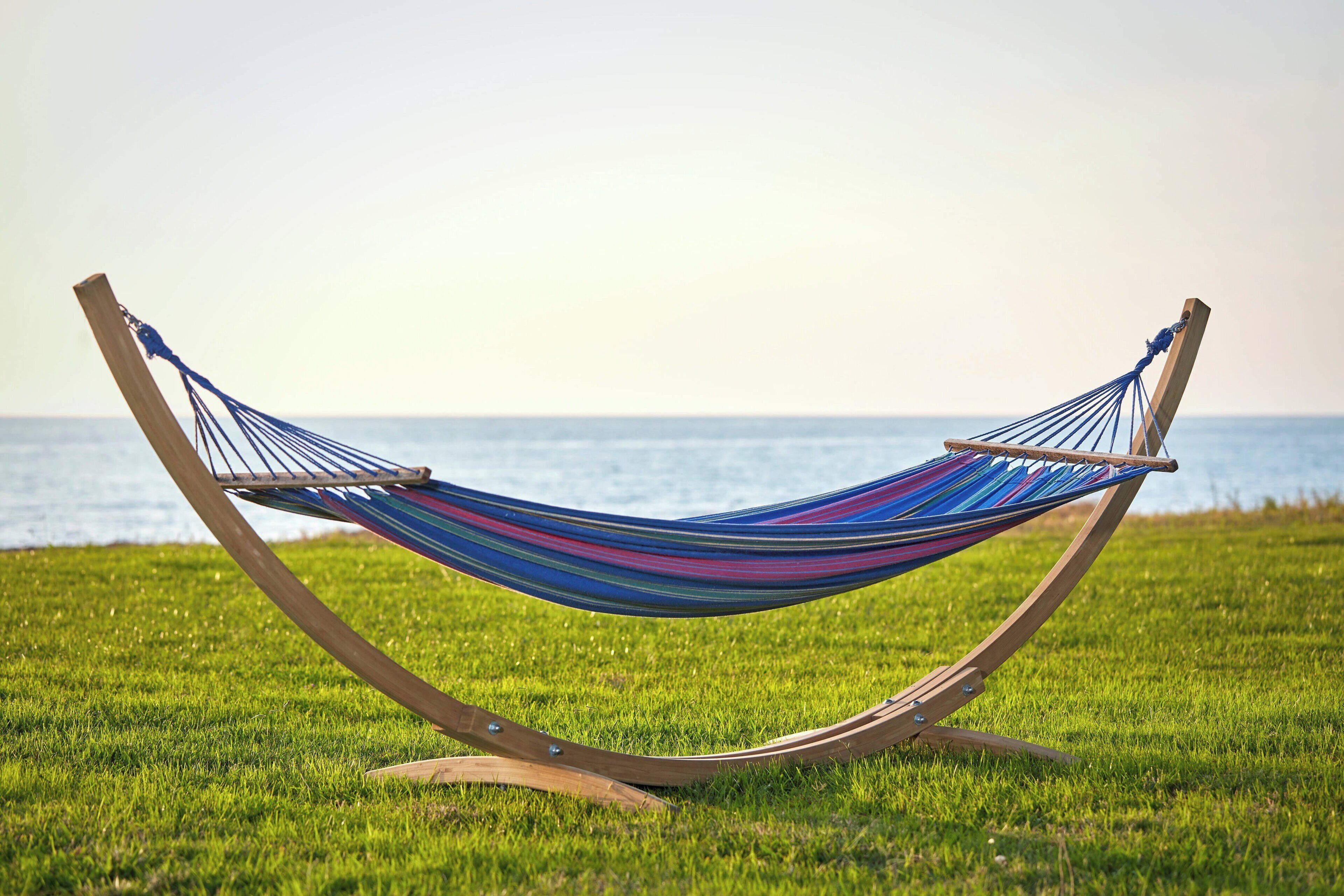 A hammock on a grassy field with a view of the sea.