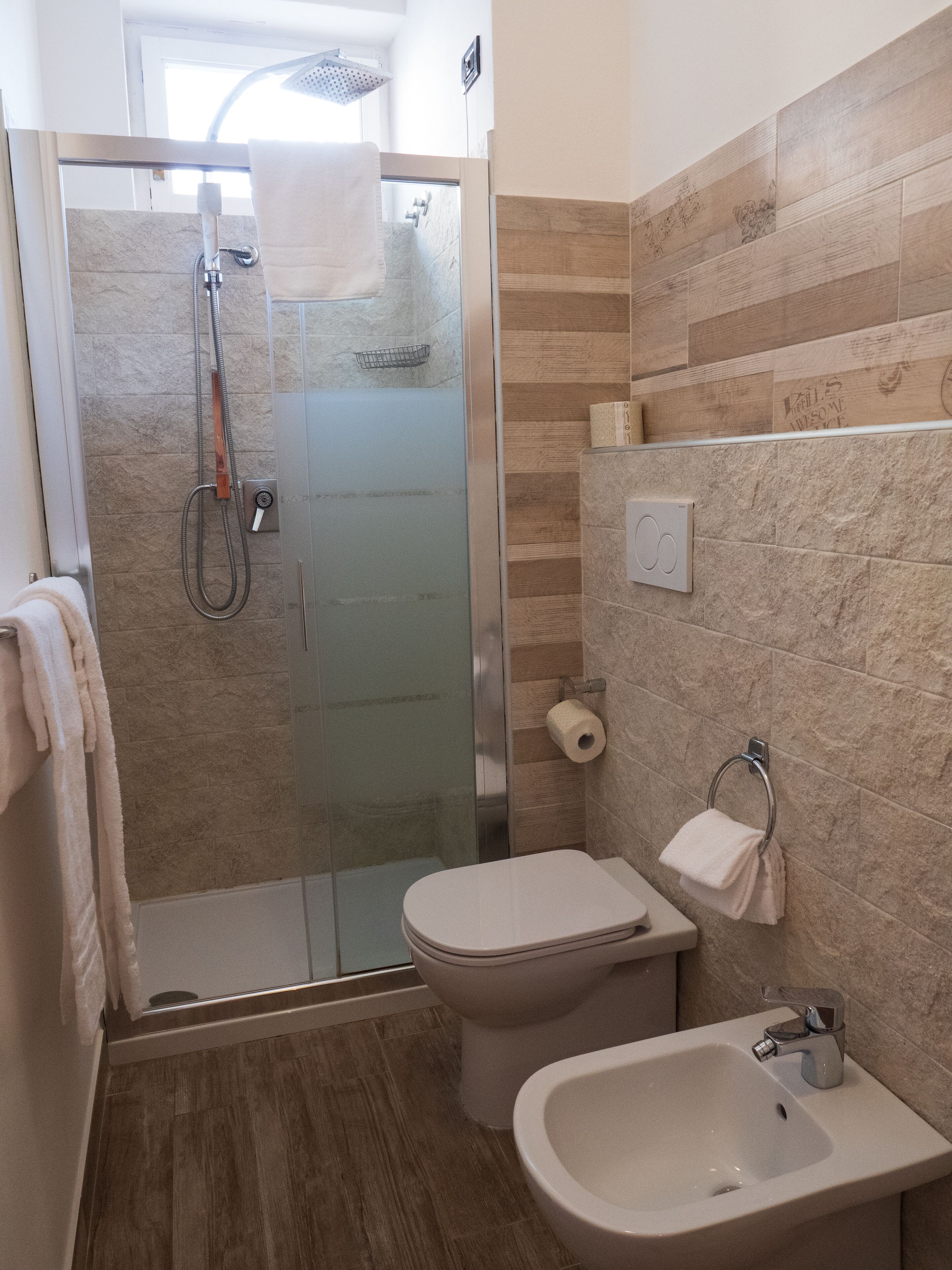 Une salle de bain avec une douche à parois de verre, des toilettes, un lavabo et un porte-serviettes.