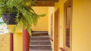 Una escalera con una planta colgante, una puerta de madera y una pared amarilla.