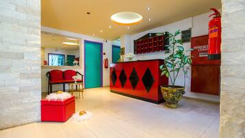 A modern lobby with a red reception desk, a teal door, and a fire extinguisher.