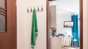 Un pasillo que lleva a una zona de cocina con una puerta de madera, una toalla verde colgada de un gancho y un letrero que indica apartamentos P&0.