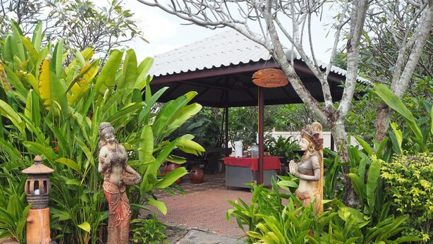 A garden with statues, a covered area, and a stone pathway. - Country Inn 304 (Si Maha Phot)