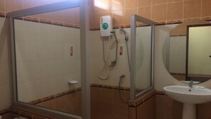 Casa de banho com chuveiro em cabine de vidro, lavatório e espelho.