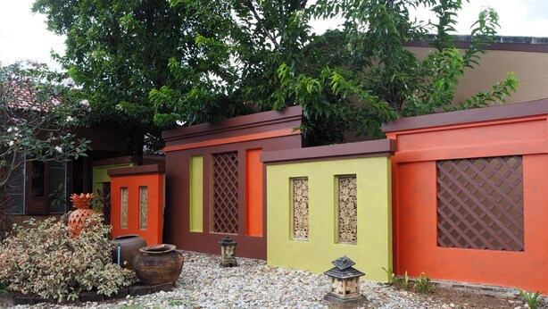 Um pátio com um pequeno jardim, um candeeiro de pedra decorativo e um telhado em azulejos.