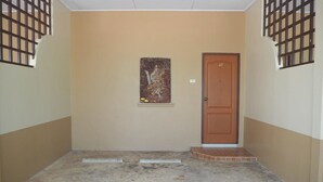 Um corredor com uma porta identificada com o número 27, uma pequena obra de arte na parede e chão de azulejos.