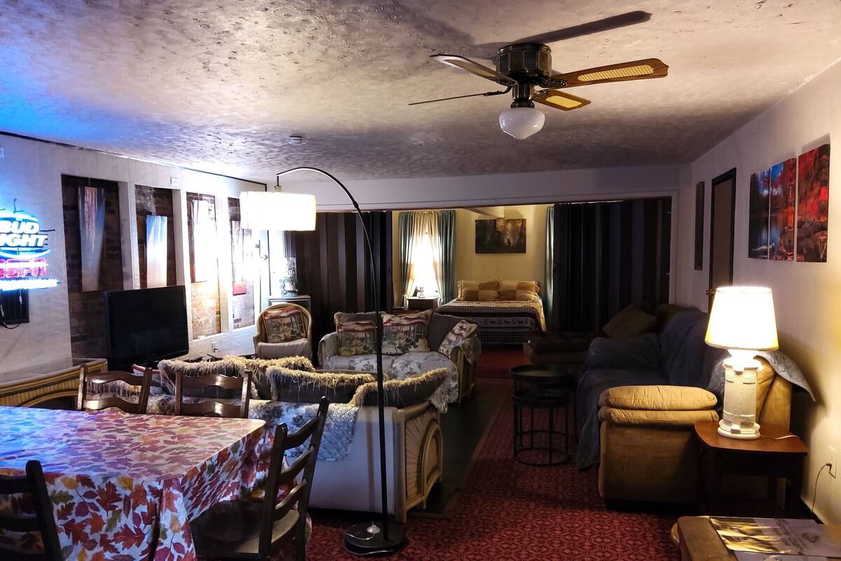 A cozy living room with a dining area, a ceiling fan, and a TV.