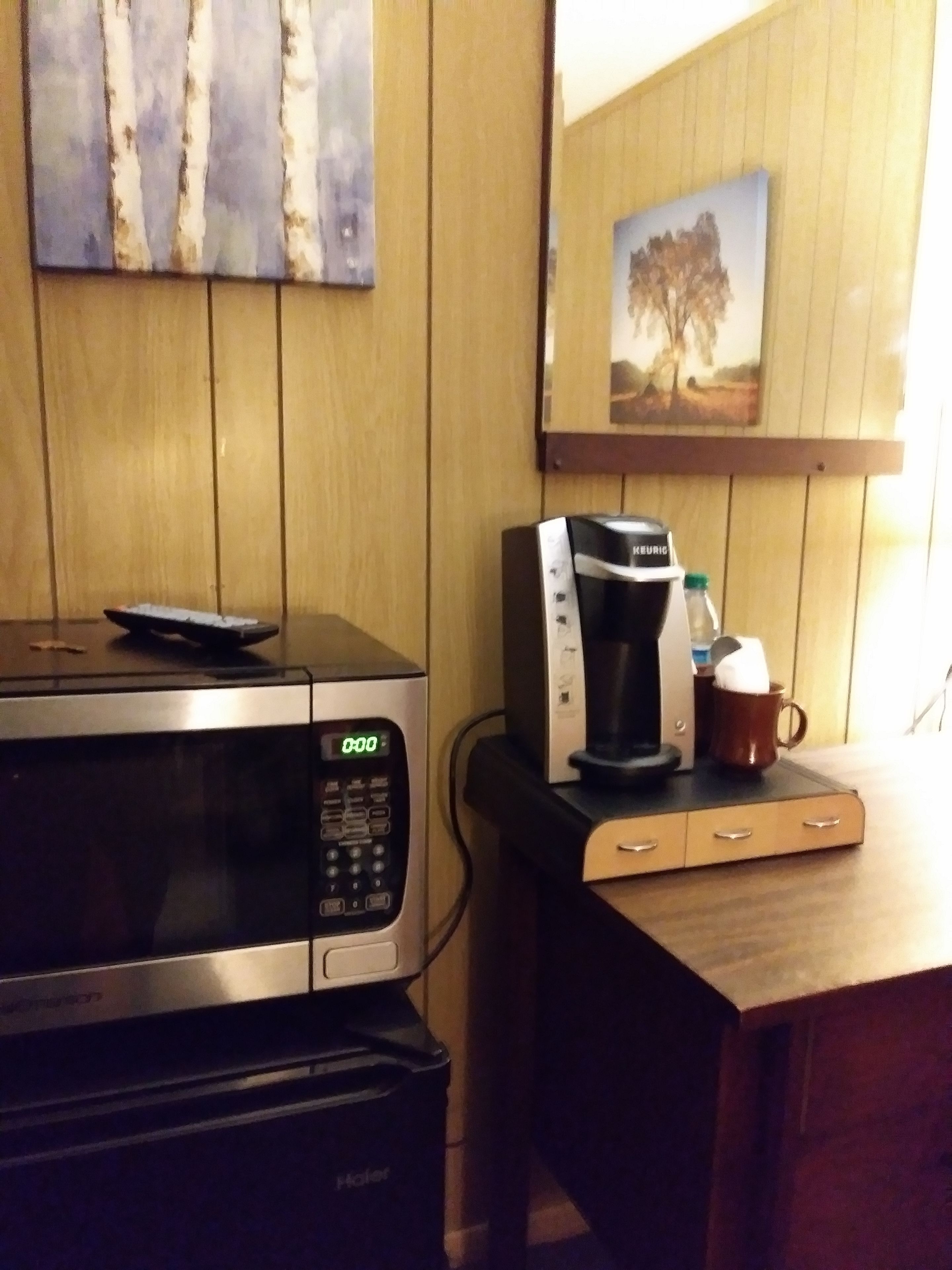 A kitchenette with a microwave, coffee maker, and a small cabinet.