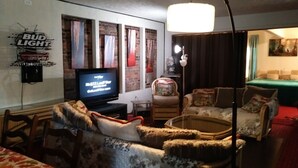 Una sala de estar con televisión, sofá, sillón y lámpara.