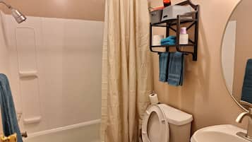 Un baño con bañera, inodoro, lavamanos y cortina de ducha.