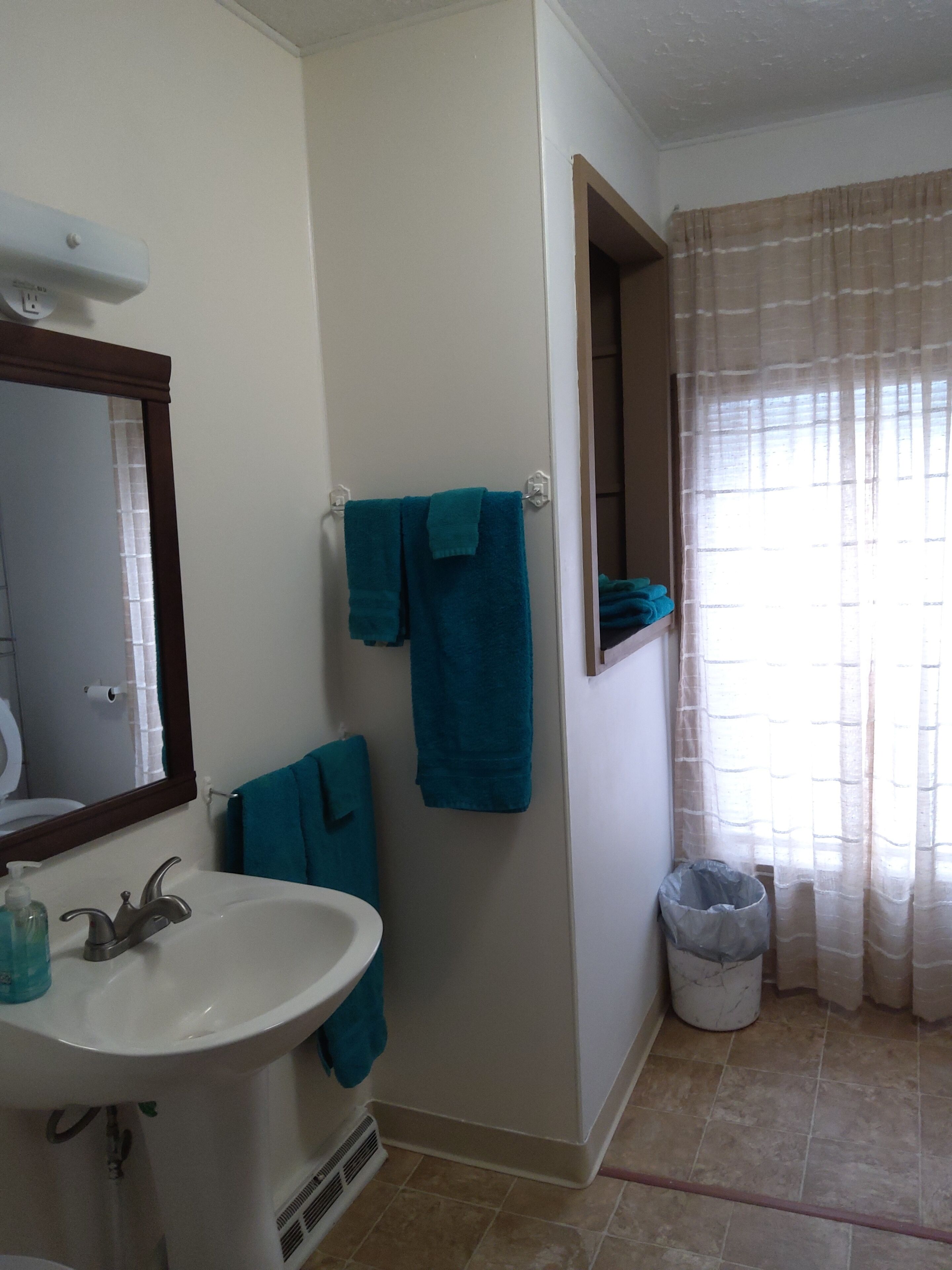 A bathroom with a sink, mirror, and two towels hanging on the wall.