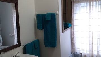 A bathroom with a sink, mirror, and two towels hanging on the wall.
