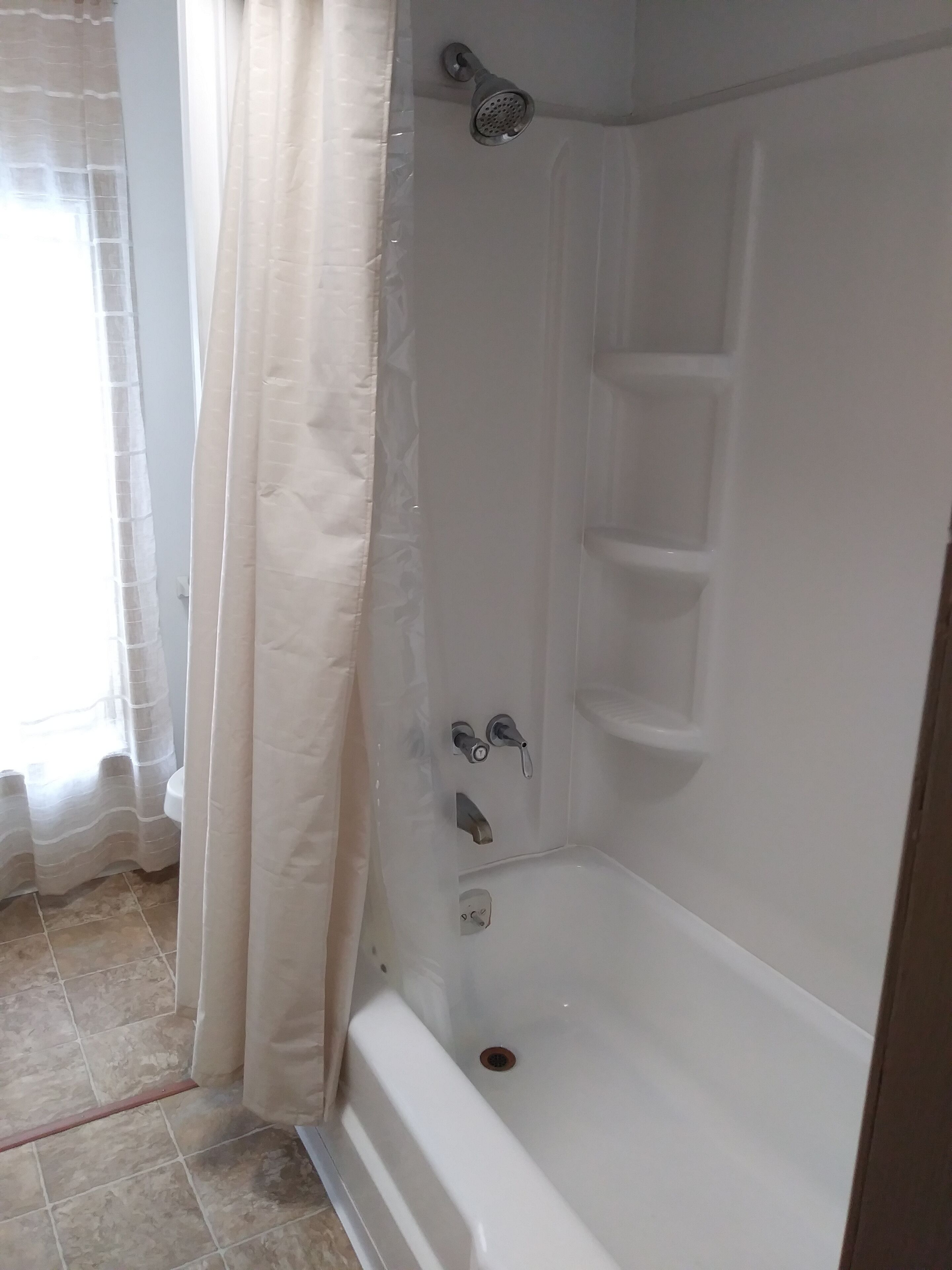 A shower with a handheld showerhead and a wall-mounted faucet.