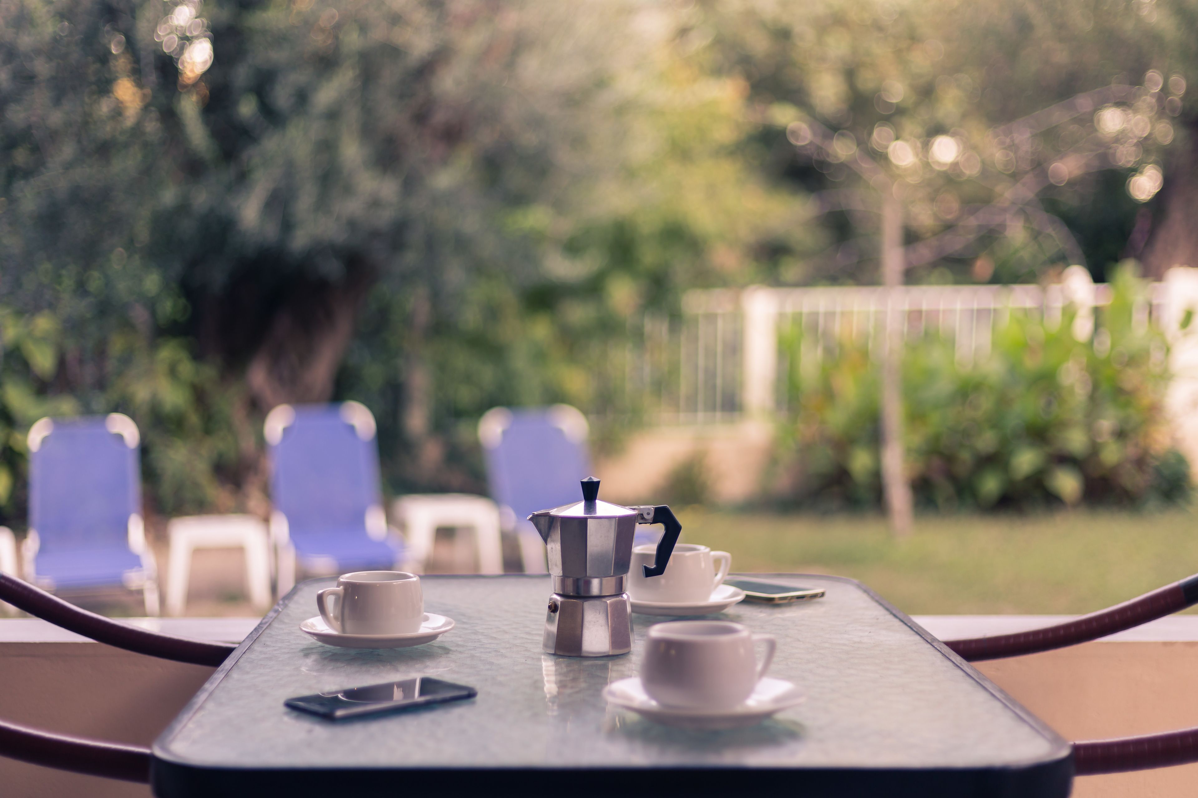 Ein Tisch mit einer Kaffeemaschine, Tassen und einem Smartphone.