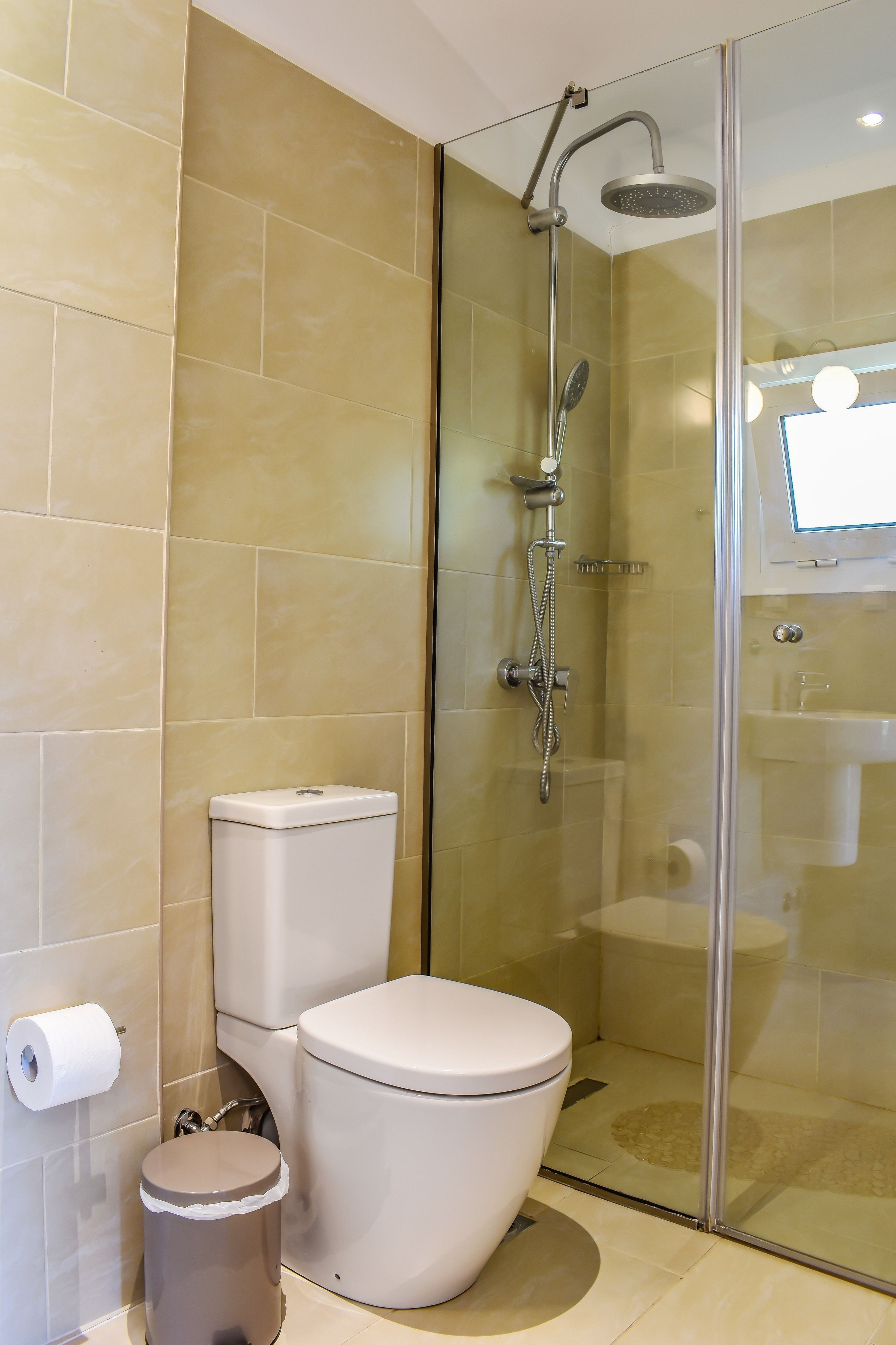 A modern bathroom with a glass-enclosed shower, a toilet, and a sink.