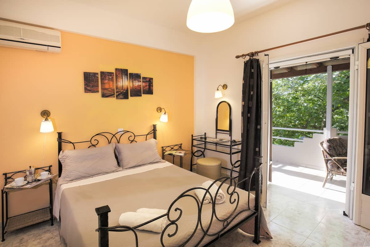 A hotel room with a bed, bedside tables, a mirror, and a balcony with a chair.
