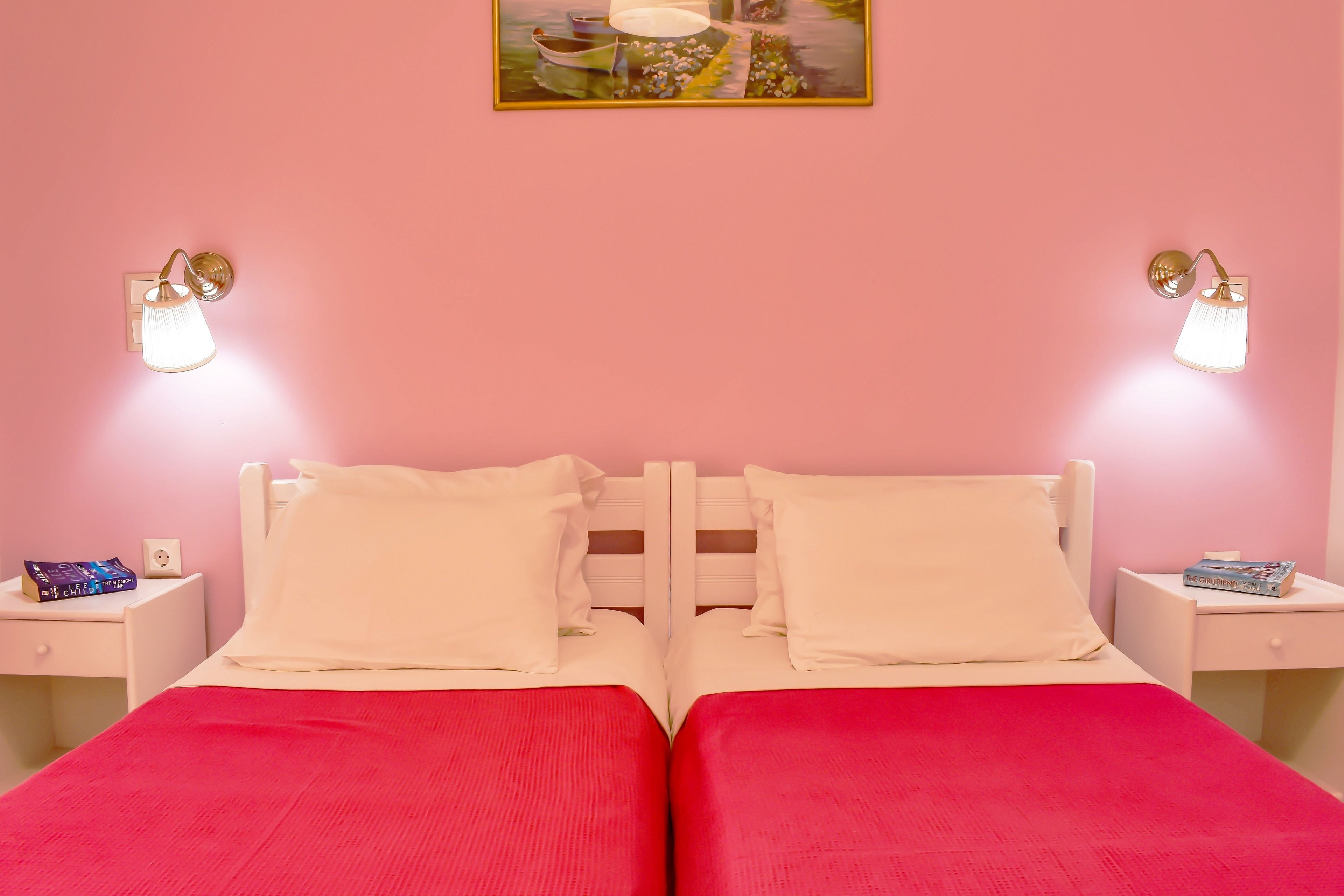 Un lit double avec deux oreillers, une couvre-lit rouge et deux tables de chevet avec des livres.