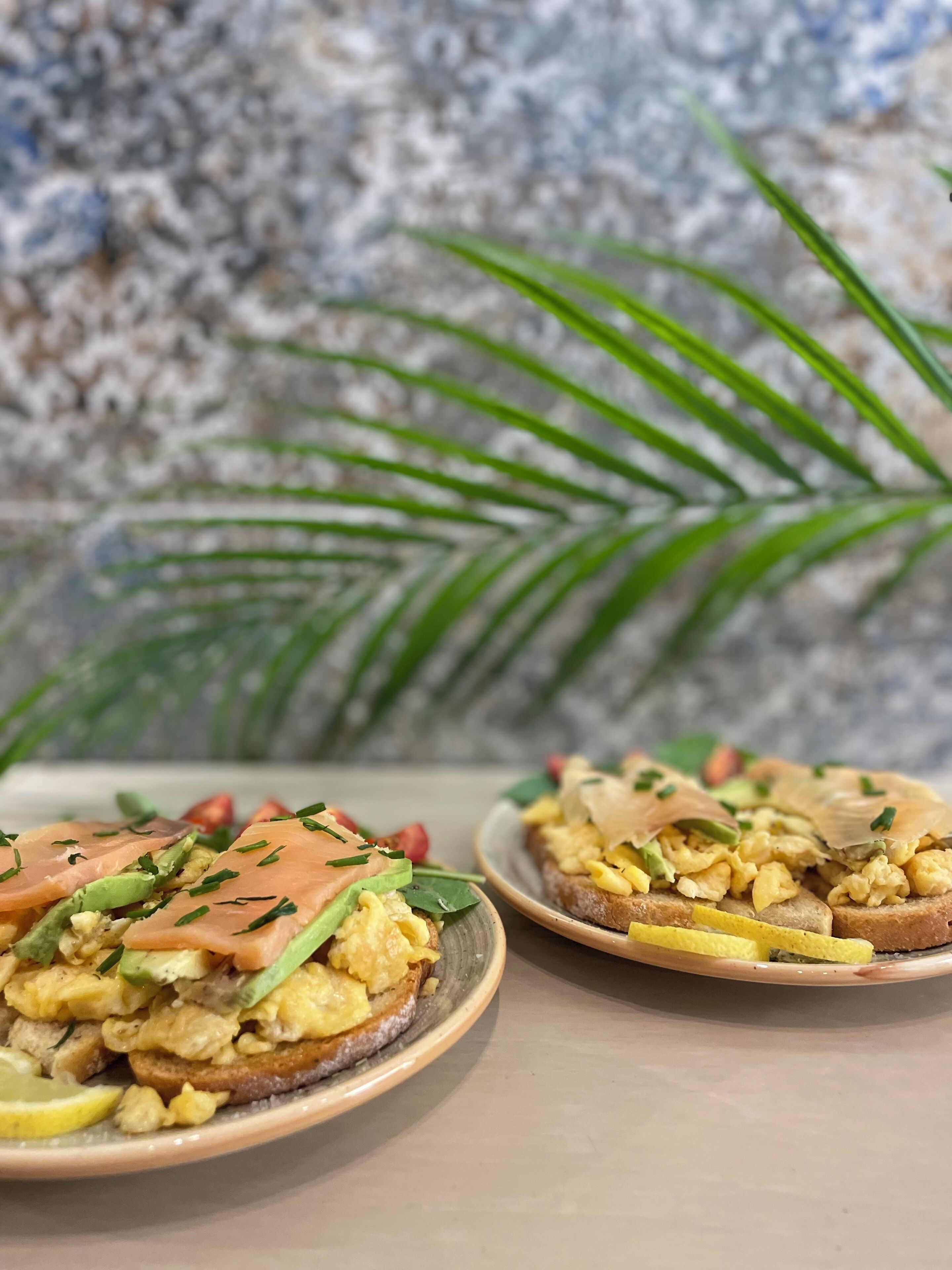 Duas porções de comida com torradas, ovos e abacate.