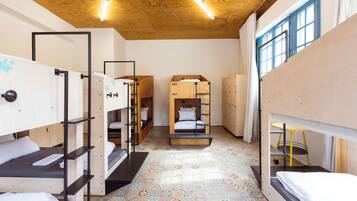 A dormitory-style room with bunk beds, a patterned floor, and a wooden ceiling.