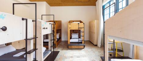 Une chambre de type dortoir avec des lits superposés, un sol à motifs et un plafond en bois.