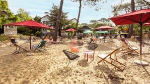 A beach with numerous colorful lounge chairs and red umbrellas.
