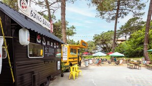 A food truck with a sign reading "Bang Bang" parked in a sunny outdoor area with tables and chairs.
