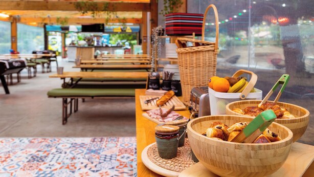 A cozy restaurant interior with wooden tables, benches, and a view through the window.
