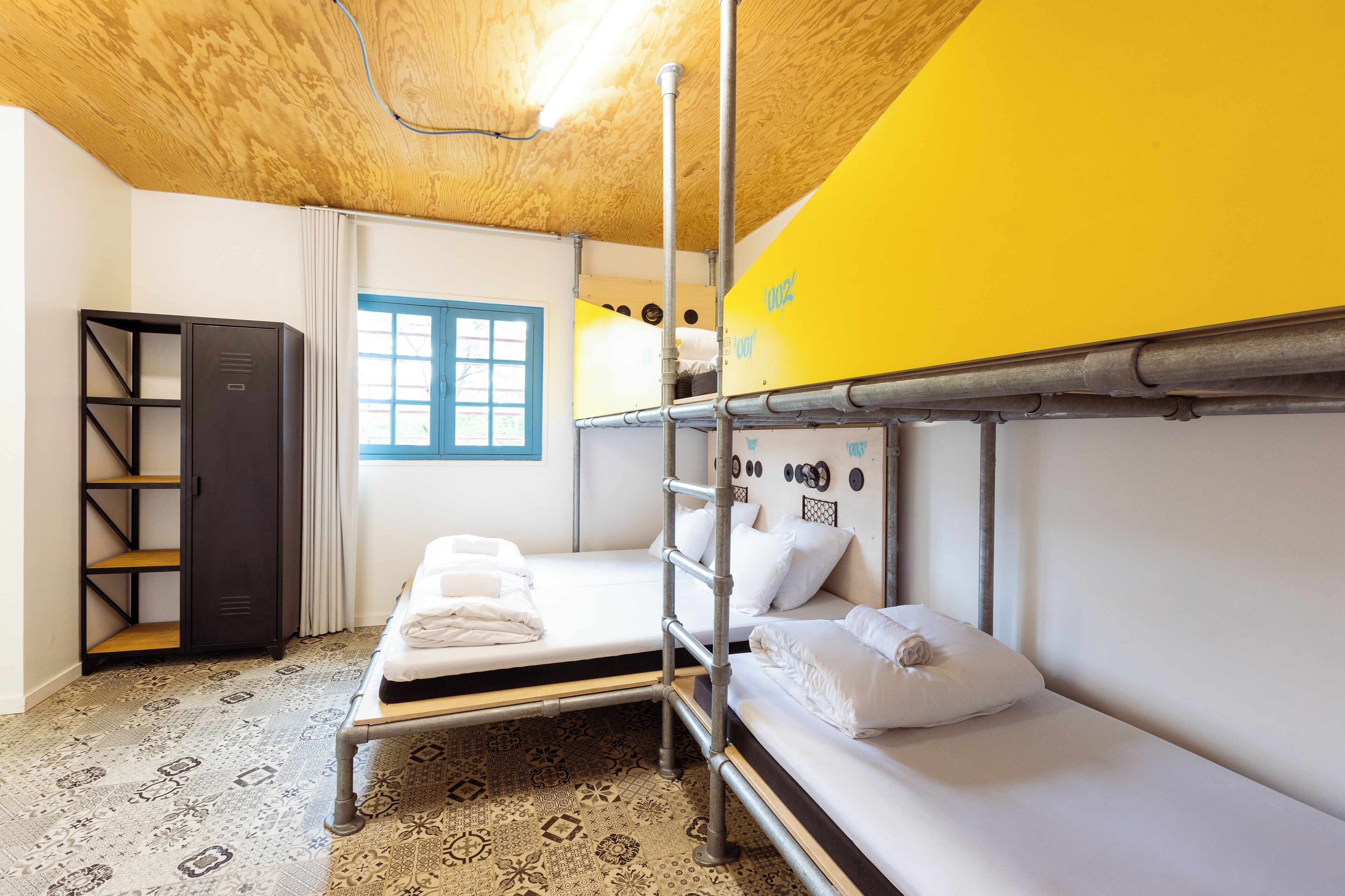Une chambre de dortoir avec des lits superposés, une armoire et un sol à motifs.