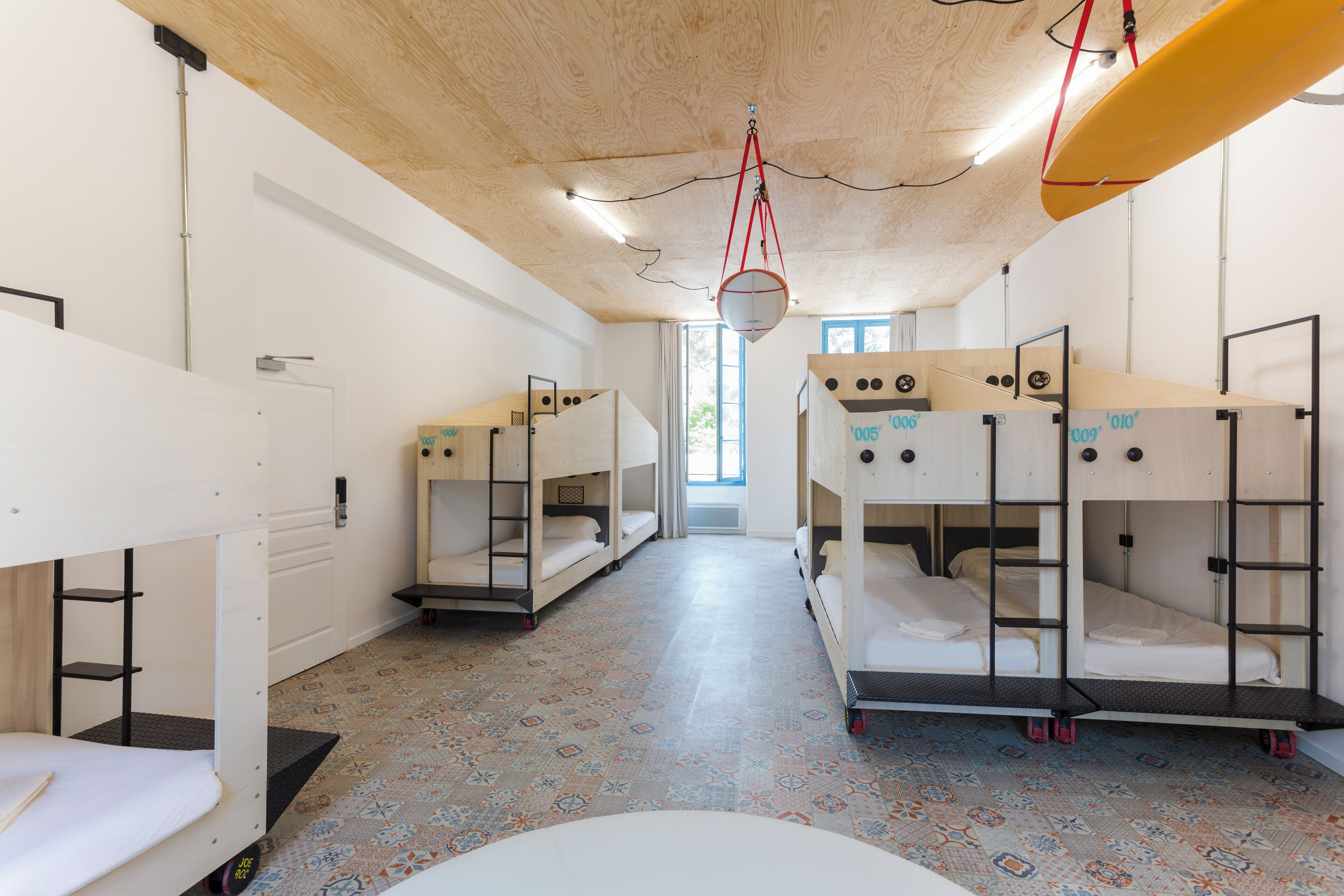 A room with bunk beds, a patterned floor, and a wooden ceiling.