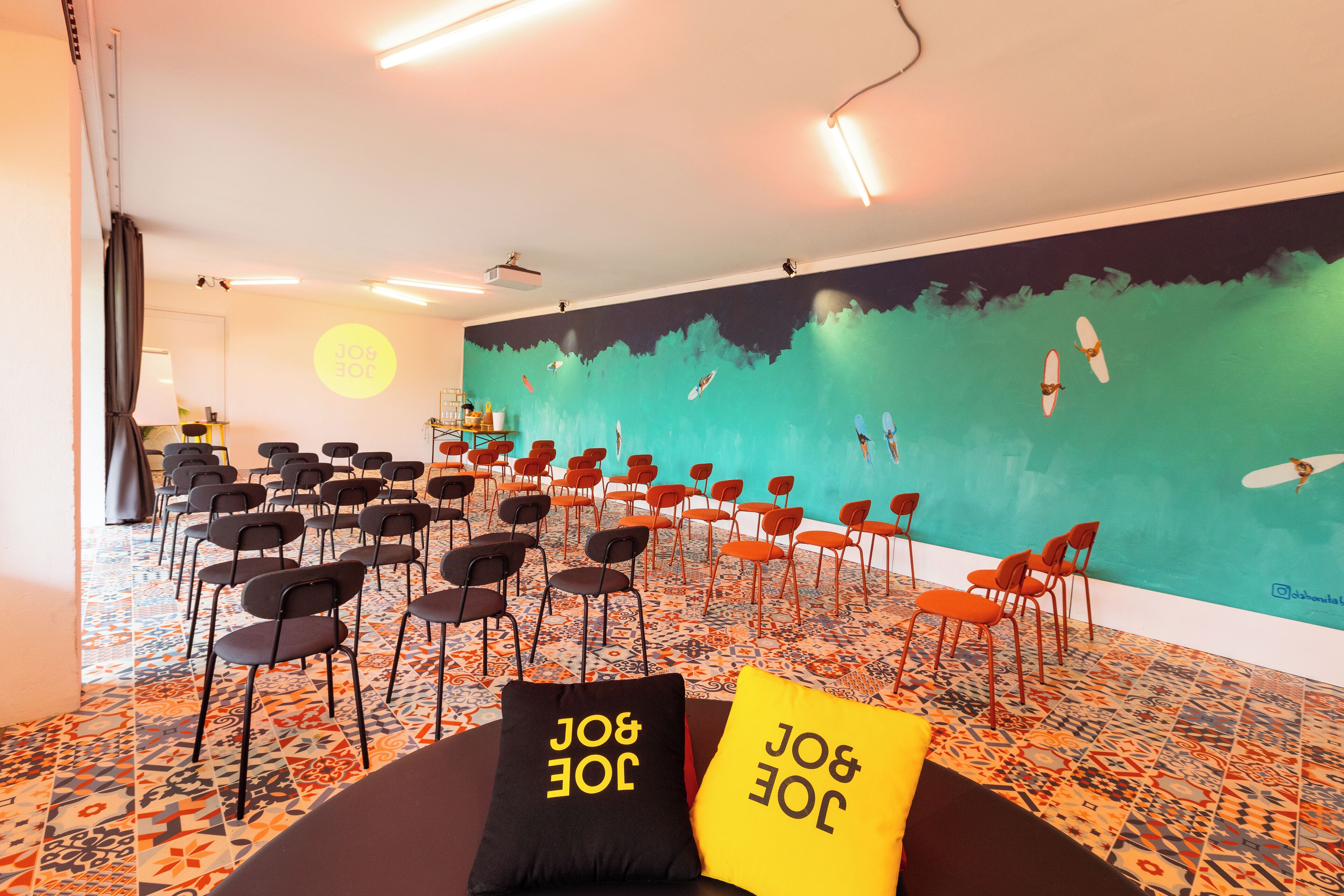 A conference room with rows of chairs, a large mural on the wall, and a patterned floor.