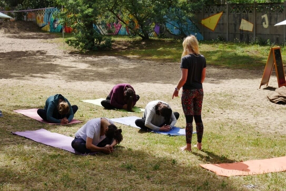 A group of people practicing yoga outdoors on mats.