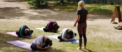A group of people practicing yoga outdoors on mats.