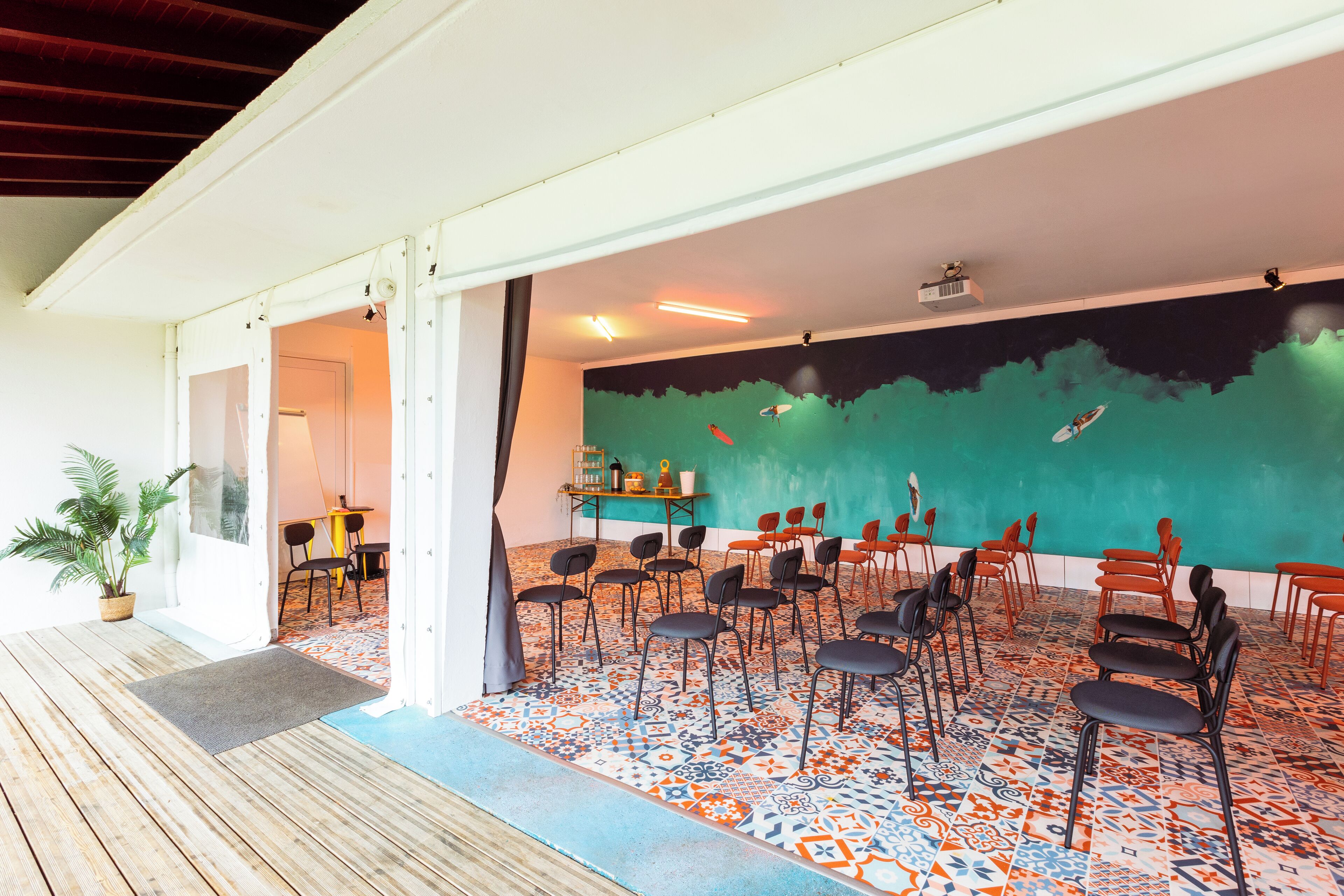 A room with a tiled floor, a green wall mural, and multiple chairs arranged for seating.