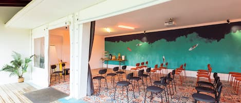 A room with a tiled floor, a green wall mural, and multiple chairs arranged for seating.