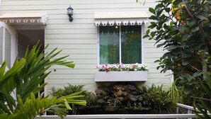 A house with a stone water feature, a window with a flower box, and a white railing. - Hello Sunny Home (Pak Chong)