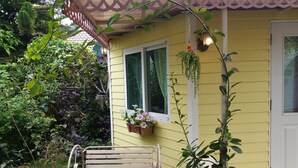 A yellow house with a white door, a bench, and a potted plant. - Hello Sunny Home (Pak Chong)