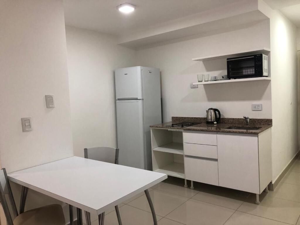 A compact kitchen with a white refrigerator, a microwave, a sink, and a small countertop.