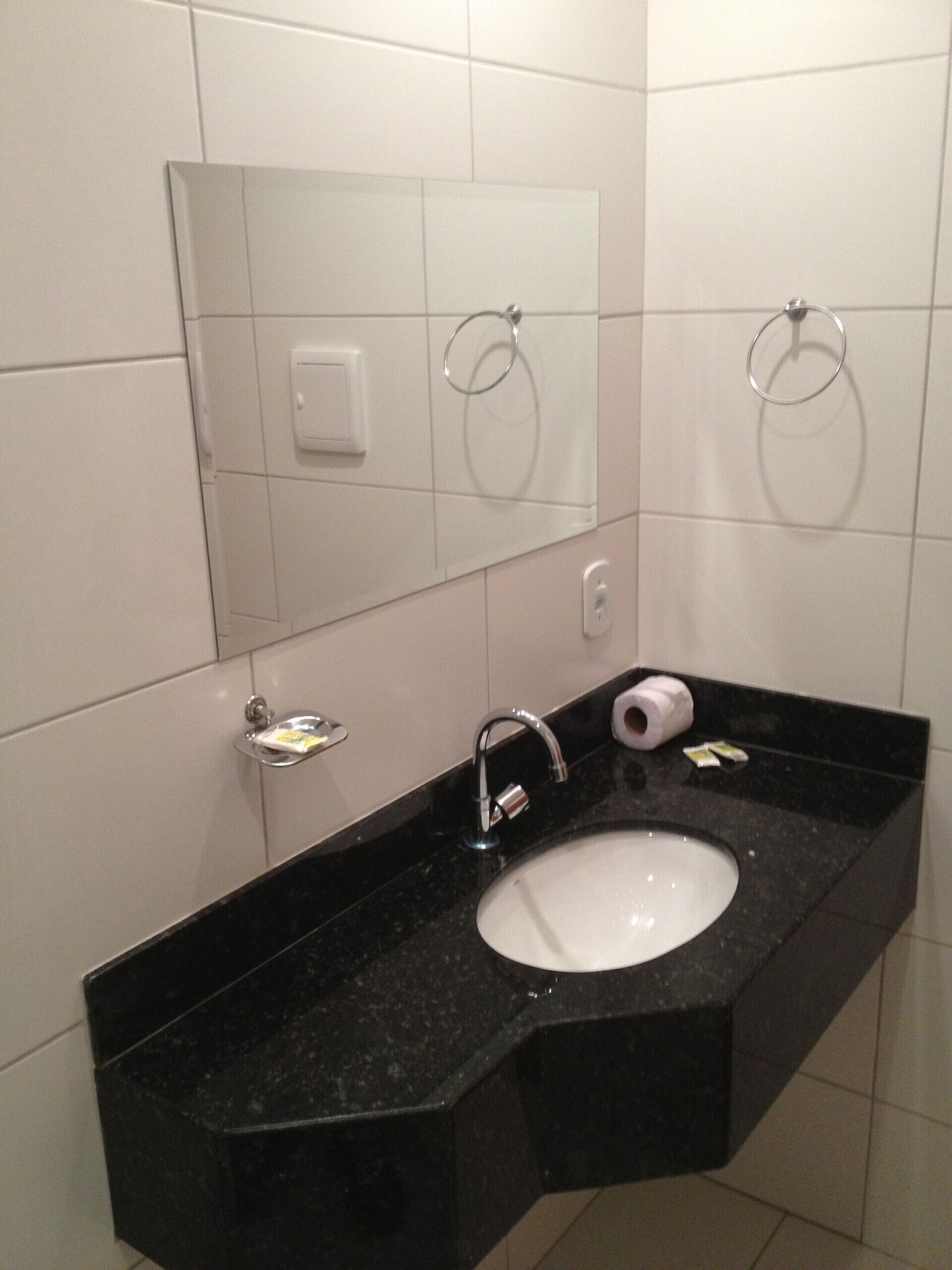 Un baño moderno con lavamanos de granito negro, un espejo y dos argollas para toallas.