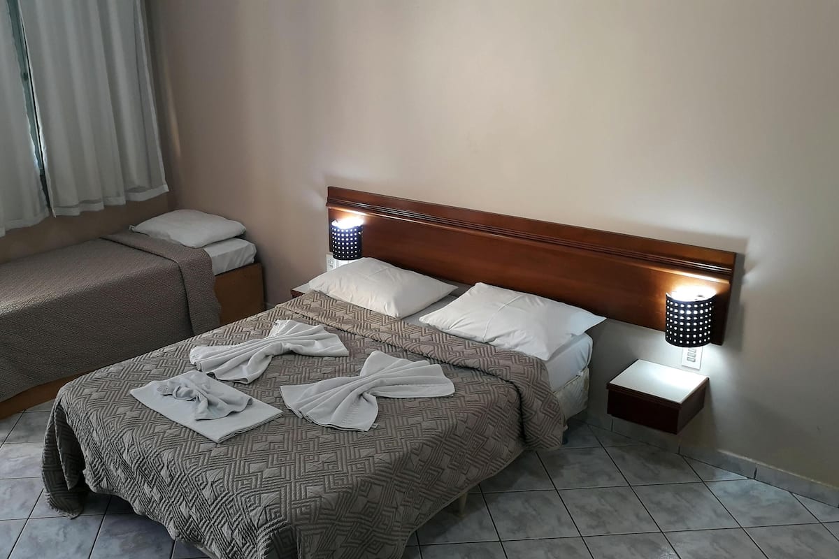 Hotellihuone, jossa on suuri sänky, kaksi yöpöytää ja kaksi seinään kiinnitettyä lamppua.