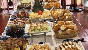 A buffet table with various food items and a vase of flowers. - Hotel Pousada Caminho da Praia (Guarapari)