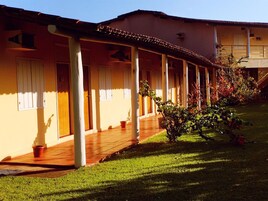 Um edifício com galeria coberta, colunas e um jardim.