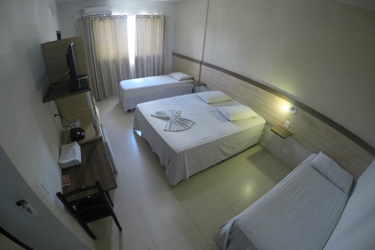 A hotel room with two beds, a desk with a telephone, and a mirror.