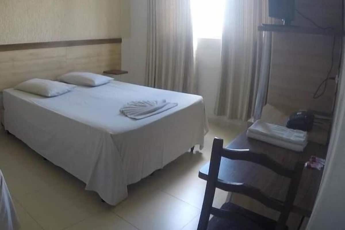 A hotel room with a single bed, a desk, and a chair.