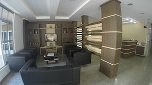 Un vestíbul modern amb una taulell de recepció, zona de seients i una gran pantalla de televisió.