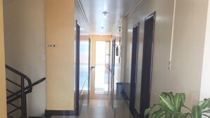 A clean, well-lit hallway with a tiled floor, a staircase on the left, and a potted plant on the right. - Hotel Skala (Foz do Iguaçu)